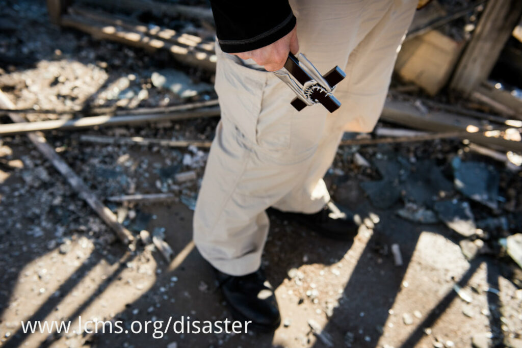 The Rev. Steven Schave, director of LCMS Urban & Inner-City Ministry, carries a cross as he surveys the remnants of the Family Dollar Store on Halls Ferry Road on Tuesday, Nov. 25, 2014, in St. Louis. The building caught fire the previous night following a grand jury decision not to indict Ferguson Police Officer Darren Wilson in the shooting death of Michael Brown. LCMS Communications/Erik M. Lunsford