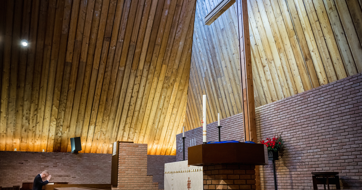 Man kneeling and praying in large church